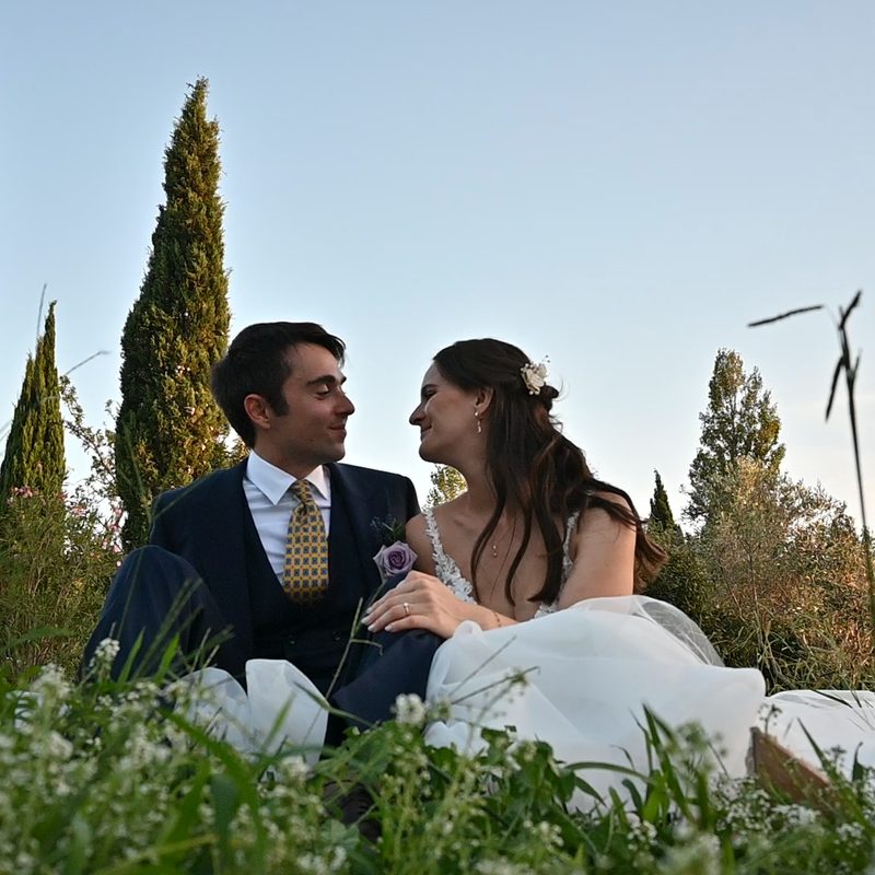 Mariés assis dans les hautes herbes, entourés de cyprès au coucher du soleil